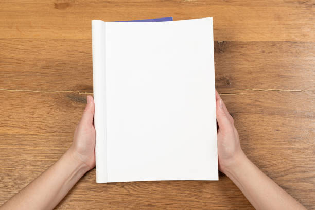 istock Woman's hands open empty catalog, magazines, book mockup on wooden table 1314711672