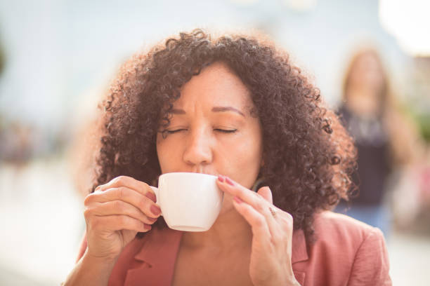 koffie in de stad.  portret van vrouw die koffie op de straat drinkt. - ogen dicht closeup vrouw 50 jaar stockfoto's en -beelden