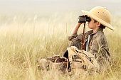 Boy looking through binoculars in a thick gray grass