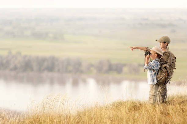 Two of little children, tourists looking into the distance on a high bluff at sunset on a summer evening