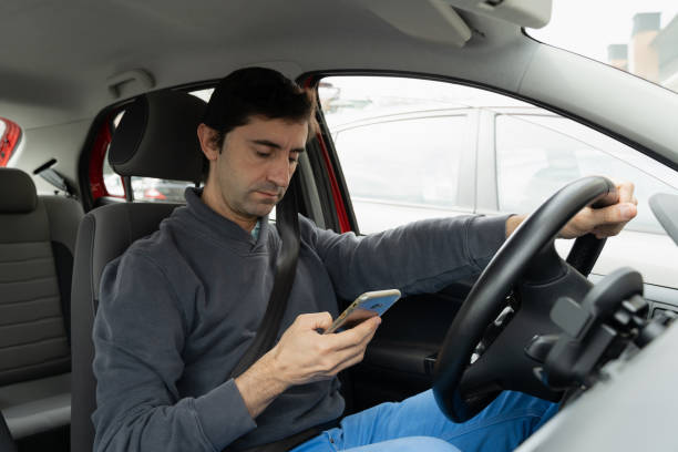 istock Man driving car looking at cellphone on hand 1314727835