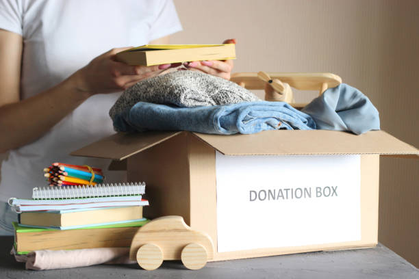 istock girl puts in a box with donations items. Volunteering 1314729212