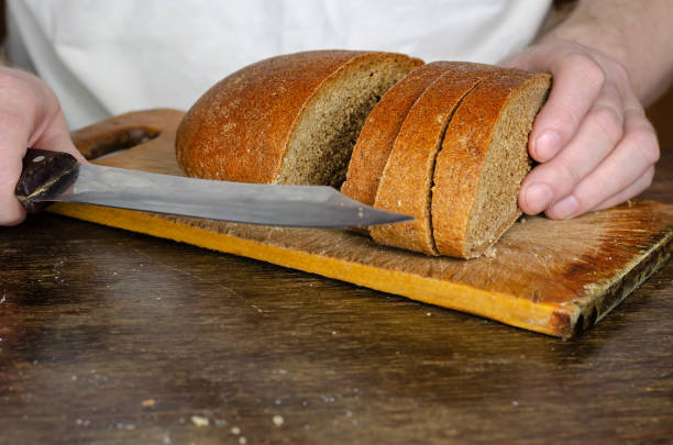 istock Hands slice bread on a wooden cutting board. 1314736592