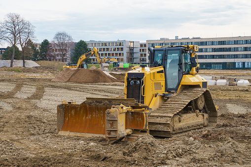Bulldozer and other construction equipment at a construction site. Buildings in the background.