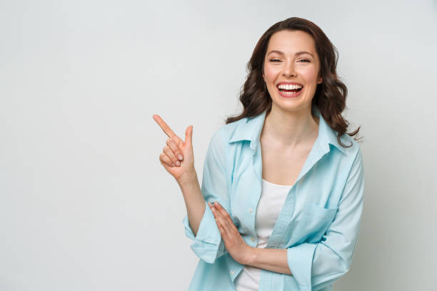 Young woman smiling and gesturing to copy space