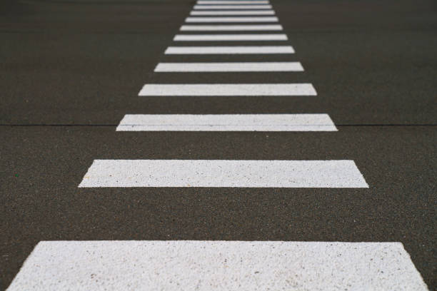 Zebra pedestrian crossing on the asphalt. The perspective receding into the distance.