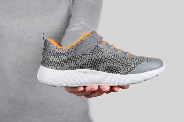 istock Hand with sport shoes on grey background 1314743290