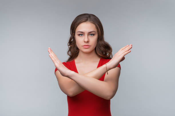 istock Serious young brunette woman showing stop gesture while looking at camera. Studio shot, gray background 1314743315