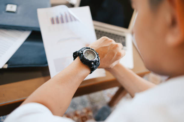 businessman looking at his watch on his hand, watching the time while working in office. - business data spreadsheet chart imagens e fotografias de stock
