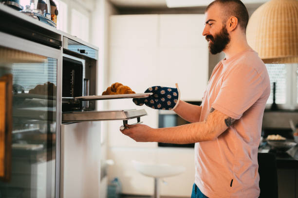 istock Young man baking croissant in the oven at home 1314744555