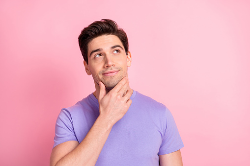 Portrait of handsome young person hand on chin look empty space thinking isolated on pink color background.
