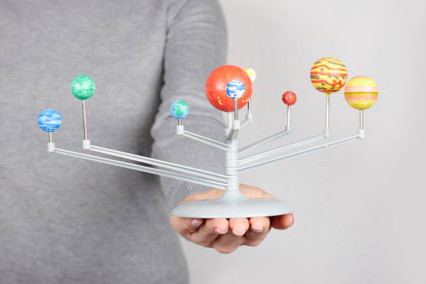 istock Hand with model of solar system on grey background 1314745048