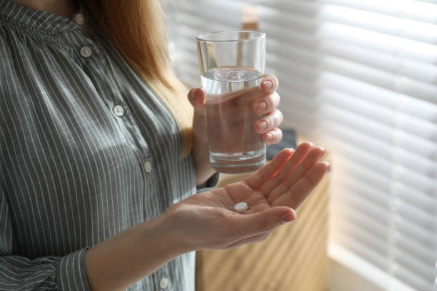 junge frau mit abtreibung pille und glas wasser drinnen, nahaufnahme - window human pregnancy home interior women stock-fotos und bilder