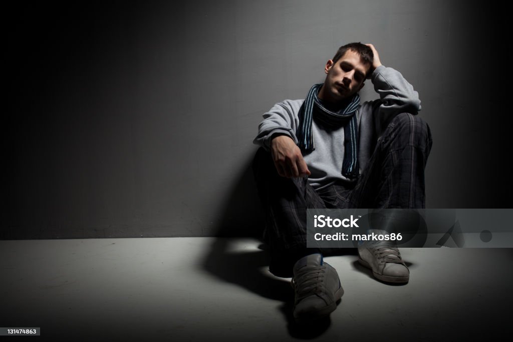 Depression Young unrecognizable male sitting on a dirty floor and having difficulties. 20-24 Years Stock Photo