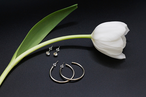 Elegant silver hoops earrings; with white tulip, black background
