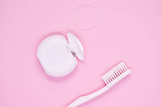 soins buccodentaire : brosse à dents blanche et soie dentaire sur fond rose. - manual operation photos et images de collection