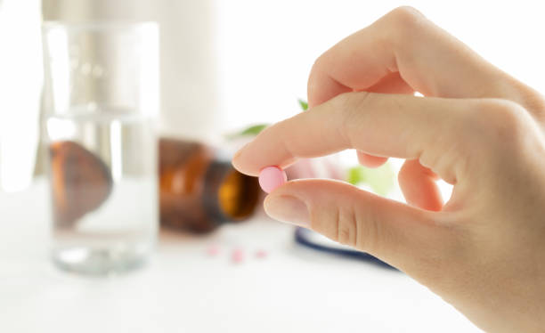istock A hand of a man hold a pill between thumb and forefinger isolated on a white background 1314758253