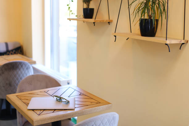 istock Image of table with closed laptop, glasses on it and chairs at cafe 1314759214