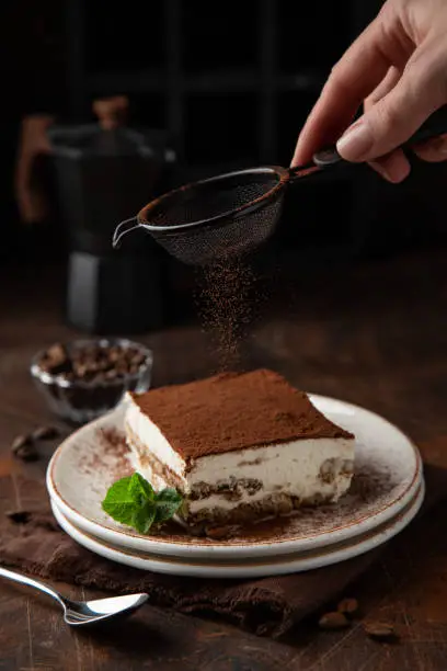 Tiramisu. Traditional italian dessert on white plate, wooden background. Selective focus