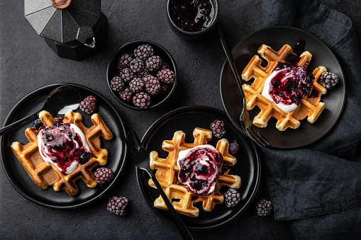 waffles with sour cream and berry sauce,  black background, top view