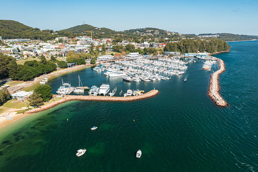 Aerial view of Nelson Bay marina, breakwater, and town with aqua waters of Port Stephens, NSW, Australia.