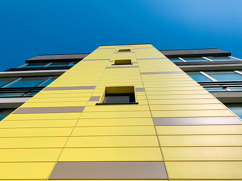 Fragment of modern luxury residential building with yellow and gray facade.