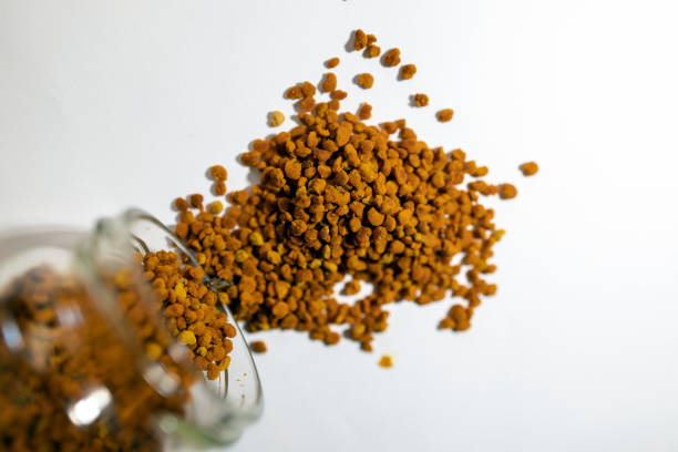 Scattered bee pollen or perga isolated on white background. Raw brown, yellow, orange flower pollen grains. Healthy food supplement
