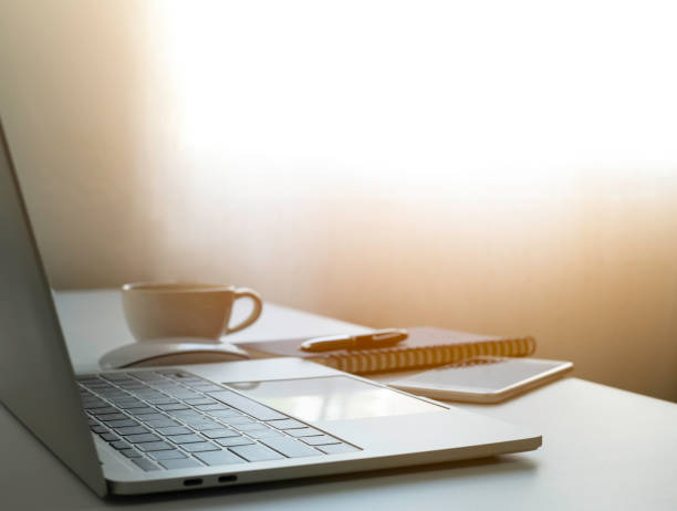 istock soft focus of Office desk table with keyboard of laptop computer, coffee cup and notebook. Business and finance concept. Workplace with morning sunlight from window with copy space. 1314768159