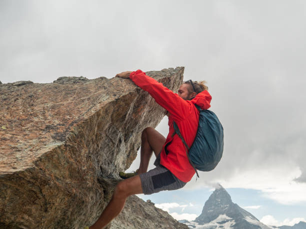 istock Sporty man climbing boulder, Matterhorn in distance 1314770593