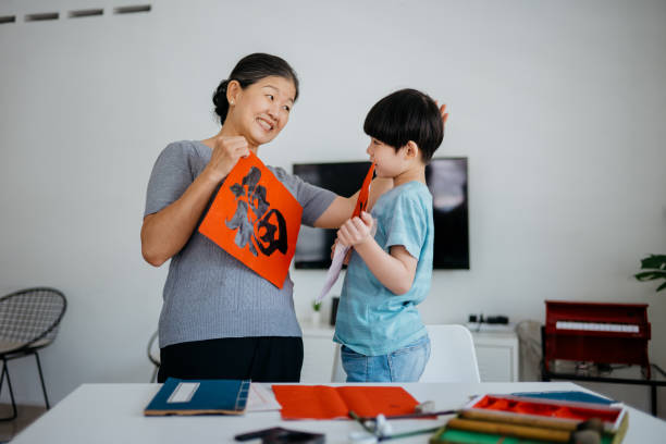 senior asian woman writing chinese calligraphy with her grandson - chinese script text calligraphy grandmother imagens e fotografias de stock