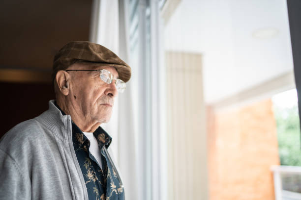 hombre mayor contemplando en casa - pensive senior adult looking through window indoors fotografías e imágenes de stock