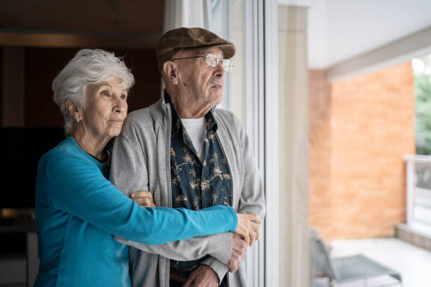 istock Senior couple looking through the window contemplating at home 1314772193