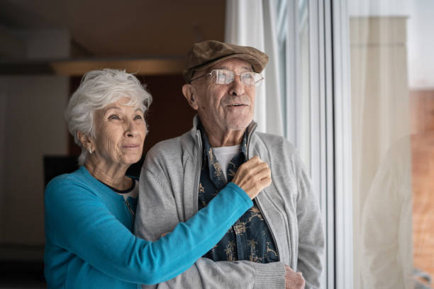 istock Senior couple looking through the window contemplating at home 1314772217