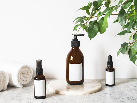 Brown glass bottles mockup for cosmetics products and cotton towels in bathroom. Front view. copy space. cosmetics products mock up. Blogging minimal beauty concept, brand packaging mock up
