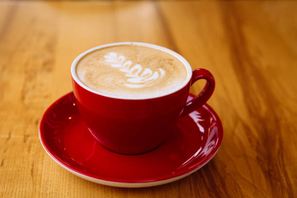istock Aromatic coffee in a red cup with milk foam and latte art on table 1314773927