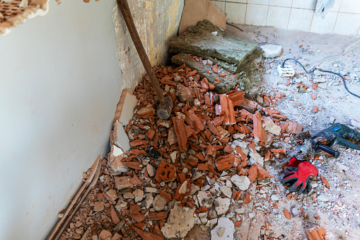 Broken pieces of ceramic tile flooring being removed with hammer. Concept of DYI home maintenance, repair, remodelling.