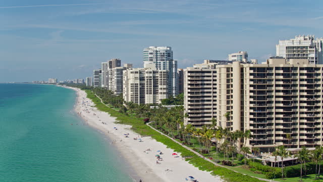Aerial skyline of Naples, Florida, with condominiums on the waterfront of the famous Naples Beach. Drone-made footage with forwarding camera motion.