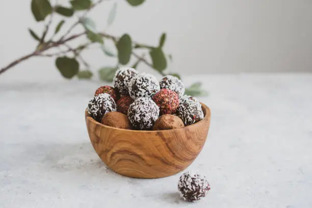 Photo of energy balls on a light table, bowl. Homemade healthy sweets