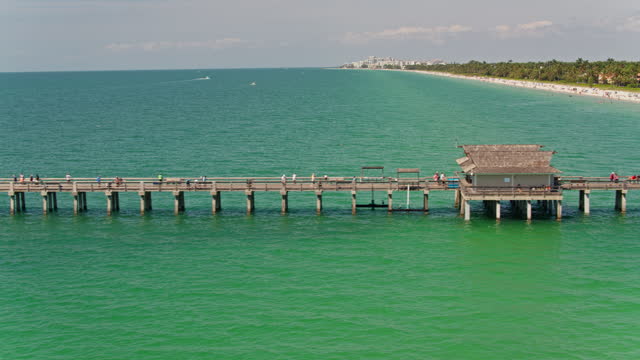 Naples Pier on the famous sandy Naples Beach, Florida. Aerial footage with wide panning camera motion.