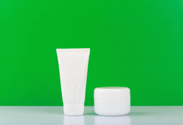 istock Face and hand cream on white glossy table against green background with space for text. 1314778950