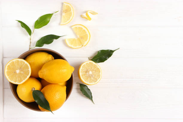 istock lemons and green leaves on a colored background. 1314779354