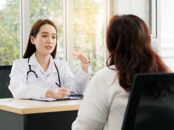 A female doctor or nurse is talking or interview a middle-aged female patient, ideas for healthcare concepts. stock photo