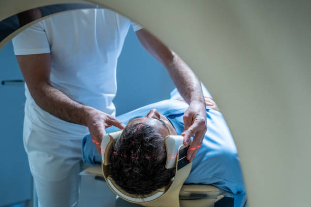 Male member of hospital staff positioning patient's head. Male member of hospital staff positioning patient's head before MRI scan. Magnetic resonance imaging technology in specialized medical clinic. doctor head stock pictures, royalty-free photos & images