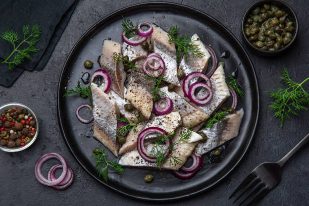 istock pickled herring with  red onion, capers and dill on black plate 1314785684