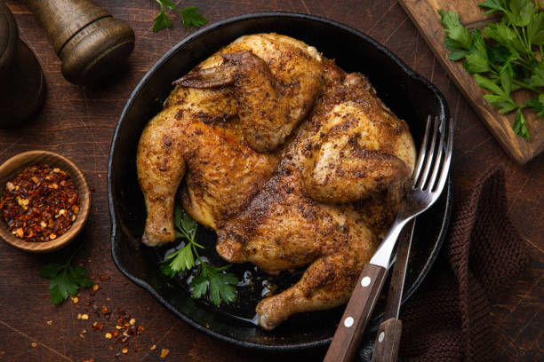 istock whole fried chicken tabaka on cast iron pan, old wooden background 1314786718