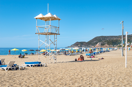 Alanya, Turkey - October 23, 2020: Rescue tower at Kleopatra Beach in Alanya. Beautiful tropical landscape with sun loungers, umbrellas and sunbathers on Mediterranean Sea on the backdrop of mountains