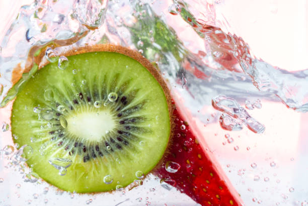 Colorful Fruit Salad with Strawberries, Kiwi, and Pomegranate Seeds served in bowl isolated on red napkin side view of healthy eating food on dark background
