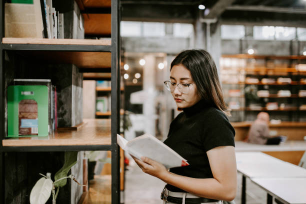 istock Young female student choosing book from shelf in library at community college 1314790214