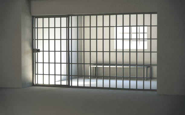 istock Prison cell interior with locked door and light shining through window. 3d rendering 1314791214