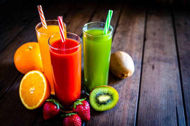 Orange, kiwi and strawberry juices on wooden table Healthy eating: high angle view of three glasses of fresh orange juice, strawberry juice and kiwi juice shot on rustic wooden table. Halved oranges, kiwi and strawberries are at the base of the glasses. The composition is at the left of an horizontal frame leaving useful copy space for text and/or logo at the right. High resolution 42Mp studio digital capture taken with SONY A7rII and Zeiss Batis 40mm F2.0 CF lens fruit juice stock pictures, royalty-free photos & images